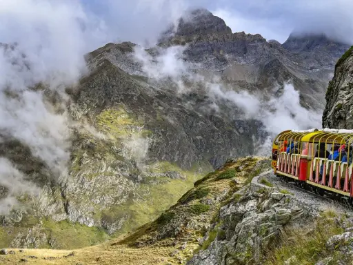 Gelber Zug fährt durch neblige Berglandschaft in den Pyrenäen, Frankreich.
