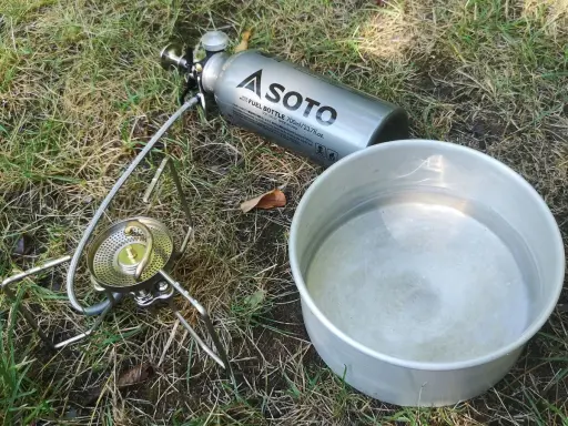 Soto Stormbreaker Kocher mit Brennstoffflasche und Topf auf Gras. Bereit für das nächste Abenteuer.