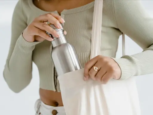 Frau verstaut ihre Edelstahlflasche in einer Stofftasche. So bleibt sie unterwegs sauber und bereit für die nächste Füllung.