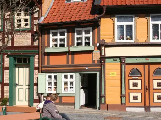 Fachwerkhäuser in Wernigerode, ein Ort voller geheimtipps. Zwei Personen sitzen auf einer Bank vor bunten Häusern.