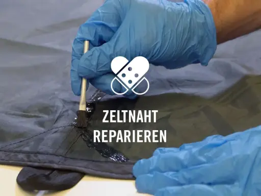 Mit einem Pinsel wird eine dunkle Dichtungsmasse auf eine Zeltnaht aufgetragen, um sie abzudichten und zu reparieren.
