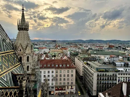 Blick über die Dächer Wiens bei Sonnenuntergang. Ein Turm des Stephansdoms ragt empor. Ein perfekter Moment, um Wien zu erleben.