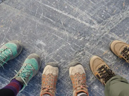 Vier Paar Wanderschuhe auf grauem Steinboden. Die Frage "wie fallen Meindl Schuhe aus?" bleibt offen, da keine Meindl-Schuhe zu sehen sind.