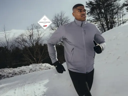 Läufer im Schnee, geschützt durch GORE-TEX INFINIUM™ WINDSTOPPER® Jacke und Handschuhe.