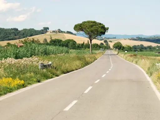 Eine Straße schlängelt sich durch die toskanische Landschaft. Perfekt, um die nächste **europa reise planen** und die Schönheit Italiens zu entdecken.