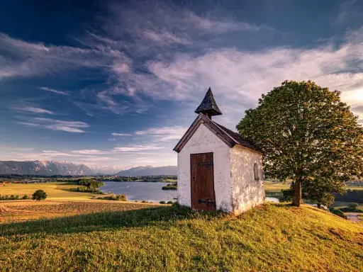 Kleine Kapelle auf einem Hügel mit Blick auf einen See und Berge. Ein **Geheimtipp Urlaub November Deutschland** für ruhige Tage.