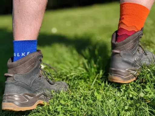 Falke TK1, TK2, TK3, TK4 Socken in Blau und Orange, getragen mit Wanderschuhen im Gras.