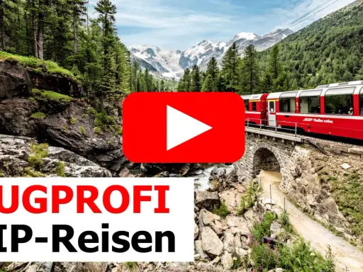 Ein roter Panoramazug fährt über eine Steinbrücke durch eine Berglandschaft mit Wäldern und schneebedeckten Gipfeln.