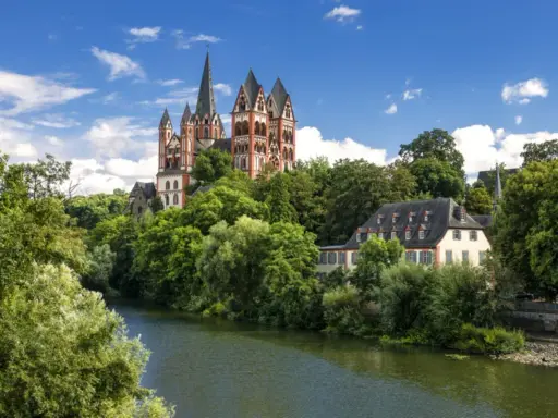 Ein malerischer Blick auf den Limburger Dom, umgeben von üppigem Grün und dem Fluss Lahn. Perfekt für einen Urlaub in Hessen.
