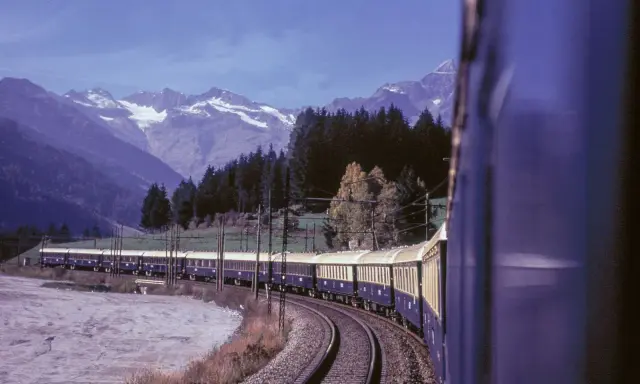 Der Istanbul Express fährt durch eine malerische Berglandschaft mit schneebedeckten Gipfeln und dichten Wäldern.