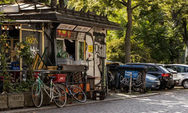 Ein Kiosk in Berlin Kreuzberg mit Fahrrädern davor und Autos dahinter.
