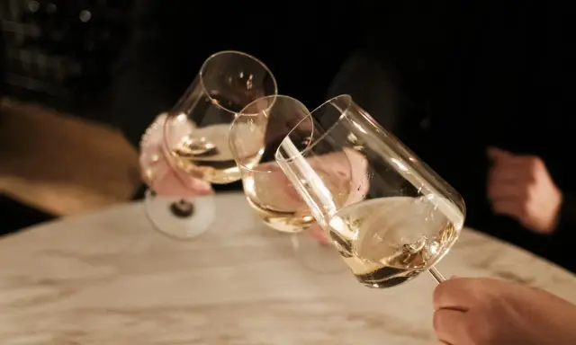 Drei Gläser Weißwein werden angestoßen. Ein schöner Moment nach einem langen Wein wandern.