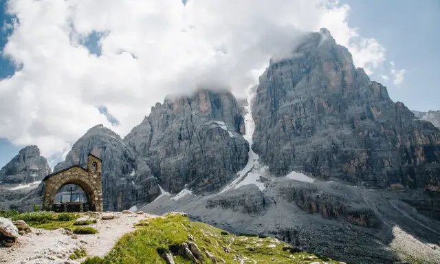 Kleine Kapelle vor imposanten Felsriesen in den Alpen. Ein perfekter Ort für mehrtageswanderungen in Europa.