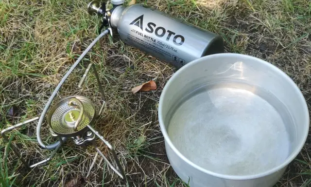 Soto Stormbreaker Kocher mit Brennstoffflasche und Topf auf Gras. Bereit für das nächste Abenteuer.