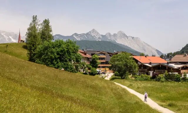 Ein Wanderweg führt durch blühende Wiesen zum malerischen Seefeld. Ein echter Geheimtipp mit Bergblick und traditioneller Architektur.