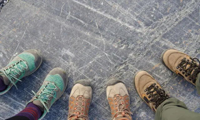 Vier Paar Wanderschuhe auf grauem Steinboden. Die Frage "wie fallen Meindl Schuhe aus?" bleibt offen, da keine Meindl-Schuhe zu sehen sind.
