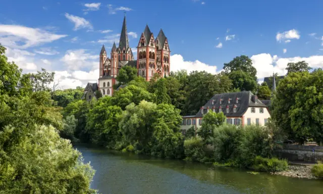 Ein malerischer Blick auf den Limburger Dom, umgeben von üppigem Grün und dem Fluss Lahn. Perfekt für einen Urlaub in Hessen.