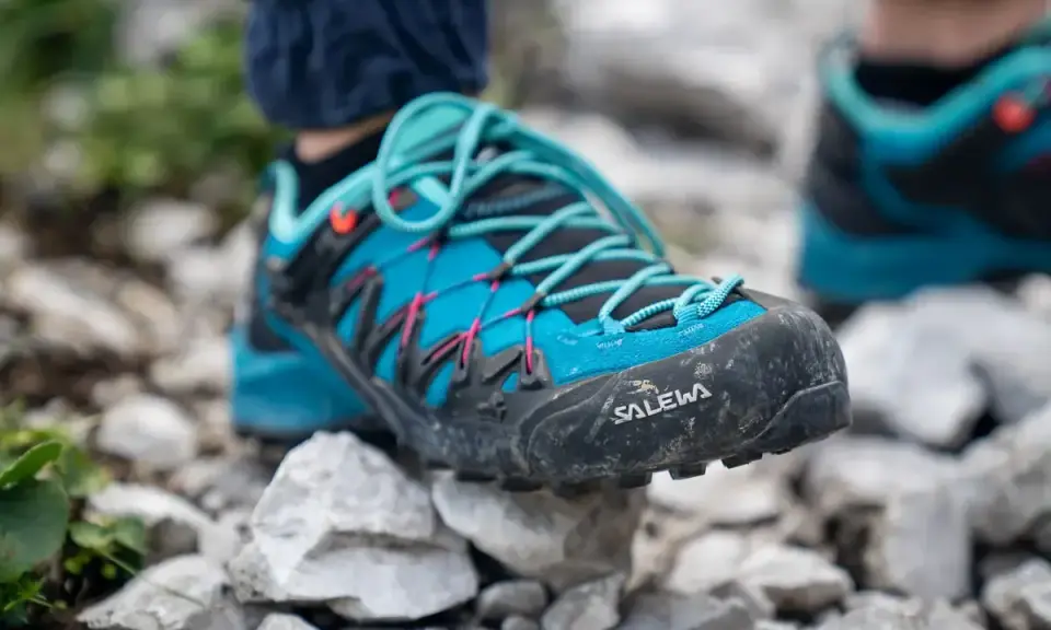 Blaue Salewa Wanderschuhe mit türkisen Schnürsenkeln, bereit für jedes Abenteuer auf steinigem Untergrund.