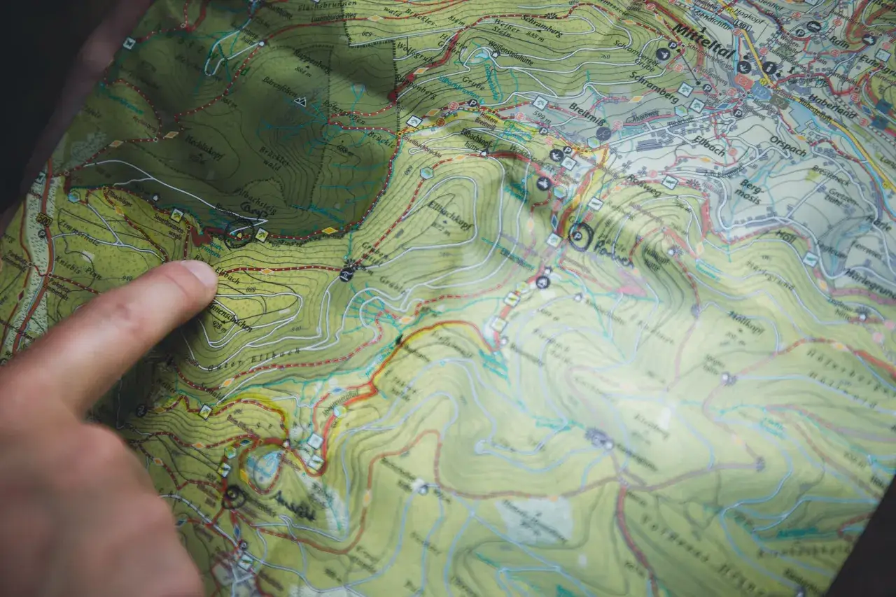 Finger zeigt auf Karte mit Wanderwegen und H&uuml;tten. Planung von Trekking Camps Deutschland.
