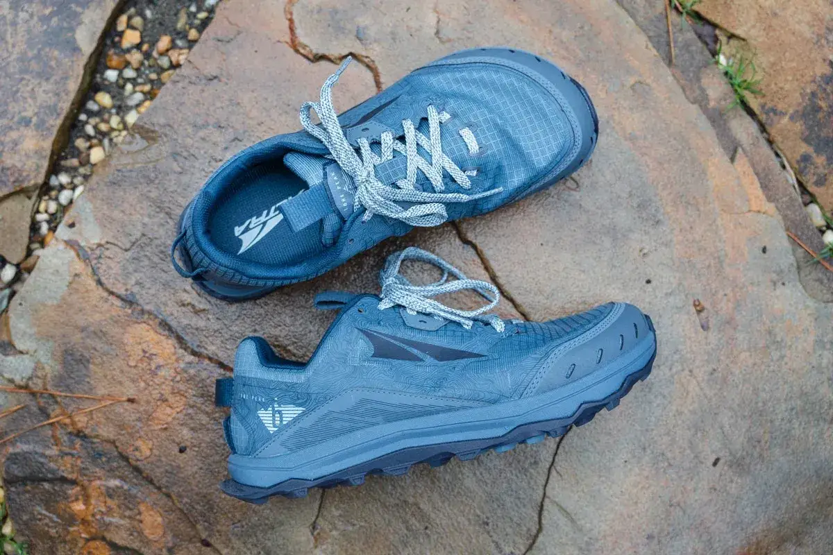 Blaue Altra Lone Peak hallux wanderschuhe liegen auf nassen Steinen. Perfekt f&uuml;r jedes Abenteuer!