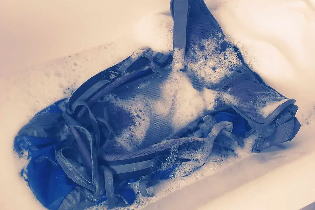 Ein blauer Rucksack wird in schaumigem Wasser gewaschen.