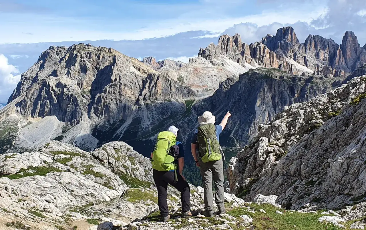 Zwei Wanderer mit Rucksäcken blicken auf majestätische Berge. Ein perfekter Ort für die besten Urlaubsziele, um die Natur zu genießen.