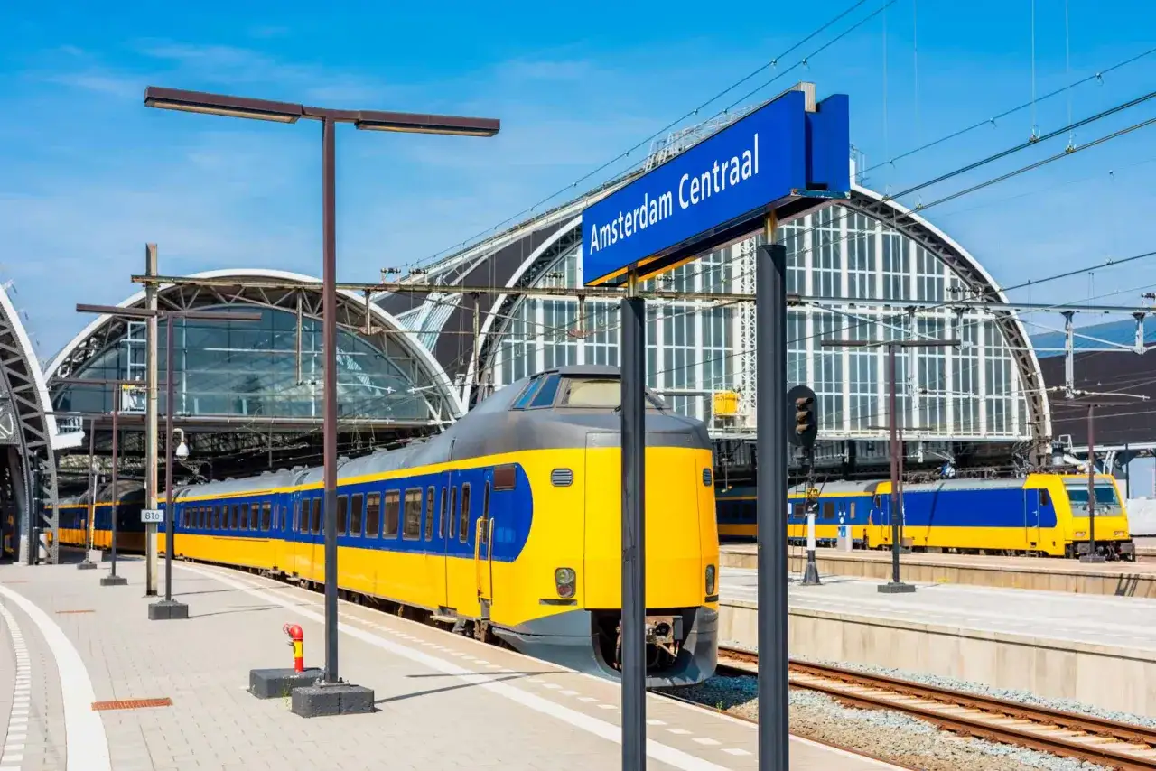 Gelber und blauer Zug am Bahnhof Amsterdam Centraal in den Niederlanden.