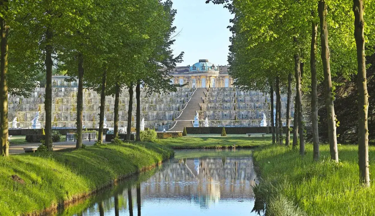 Schloss Sanssouci mit Weinbergterrassen und Wasserspiegelung. Ein perfekter Ort, um zu entdecken, was man in Potsdam machen kann.