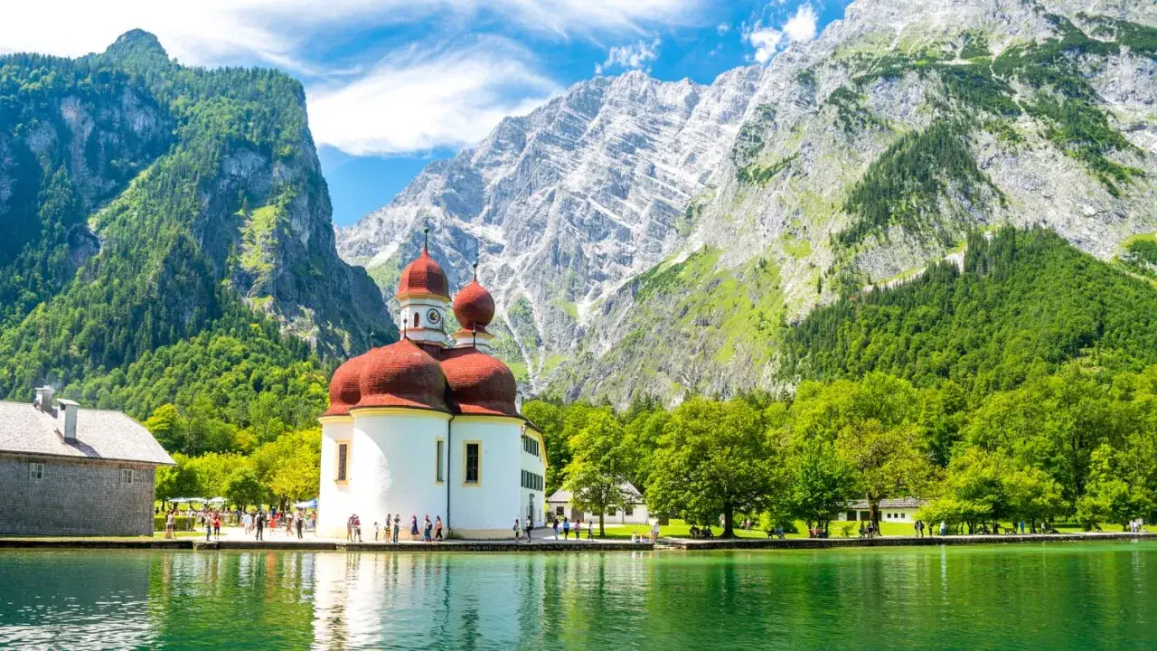 Idyllischer Sommerurlaub in Bayern: Wallfahrtskirche St. Bartholom&auml; am K&ouml;nigssee vor imposanter Bergkulisse.