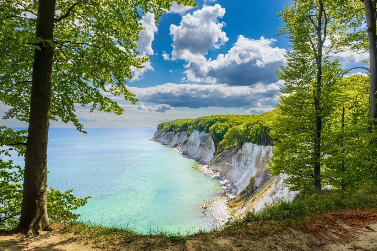 Traumhafter Urlaub im Mai in Deutschland: Kreidefelsen und türkisfarbenes Meer unter blauem Himmel mit Wolken.