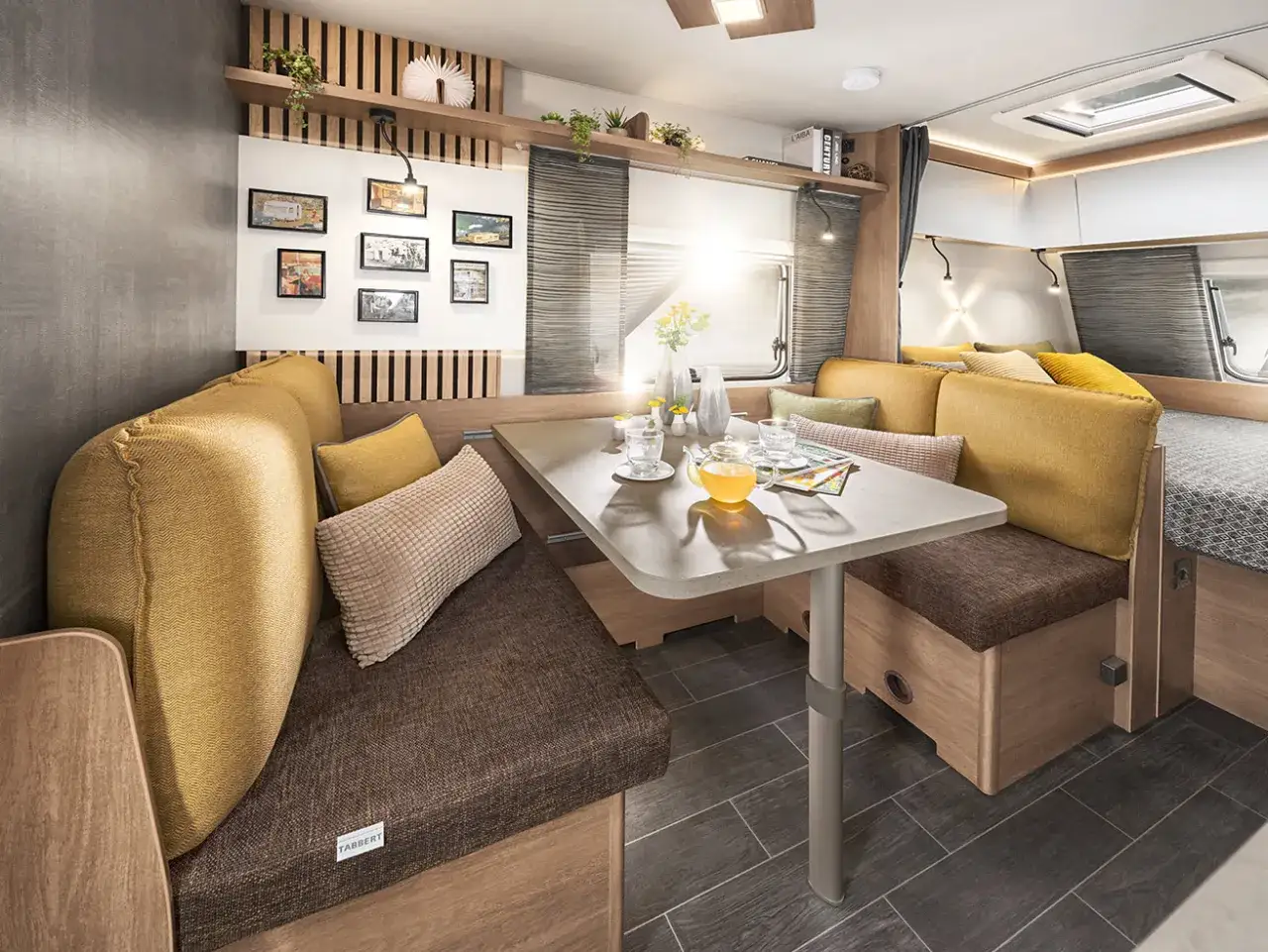 Gem&uuml;tliche Sitzecke in einem Freeway Camper mit Tisch, Kissen und Blick auf das Bett.