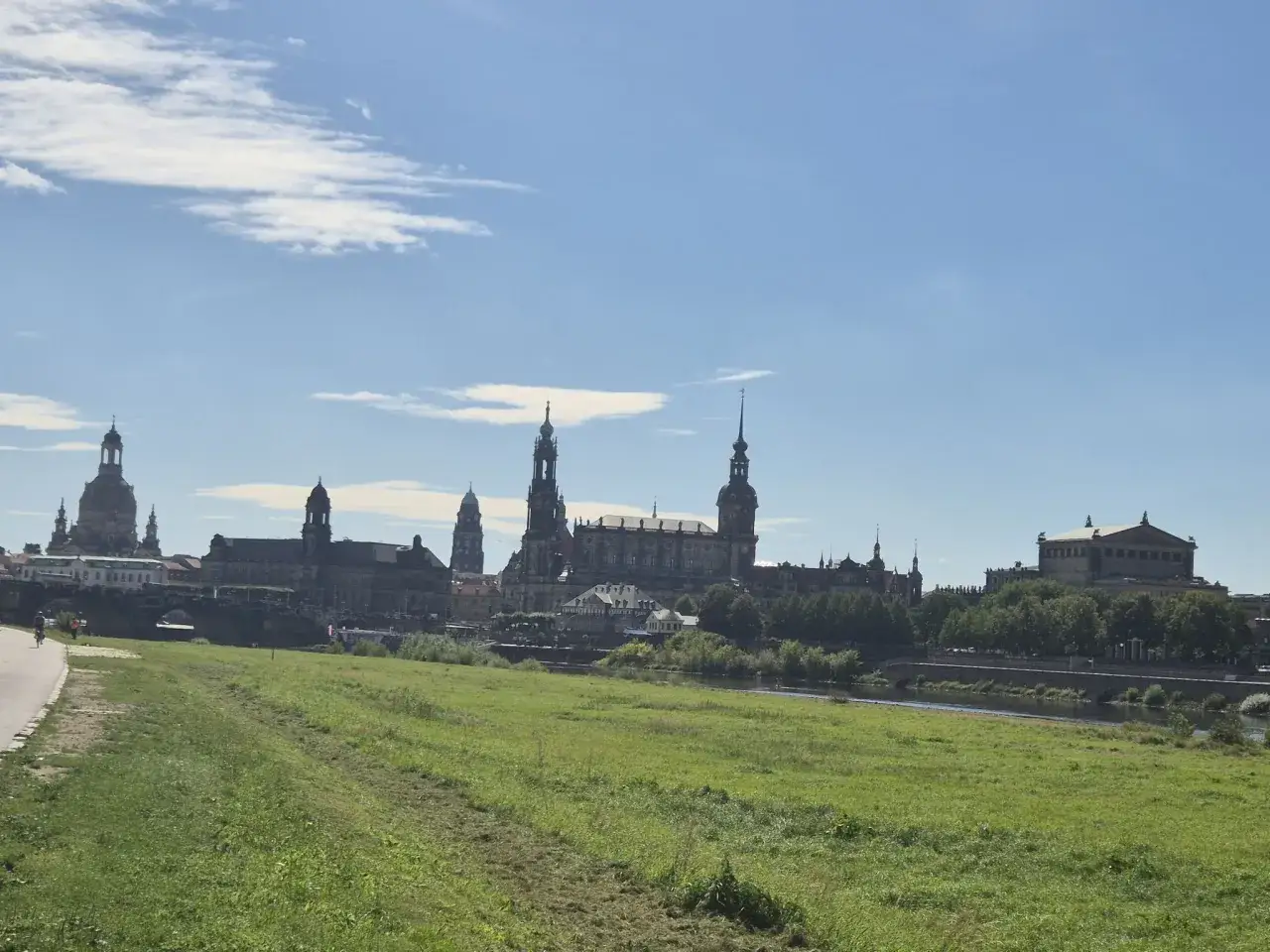 Gr&uuml;ne Wiesen und die Elbe laden ein, Dresden zu erleben. Im Hintergrund ragt die beeindruckende Silhouette der Altstadt mit ihren T&uuml;rmen und Kuppeln auf.