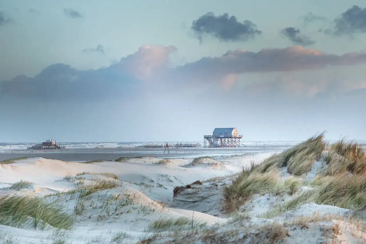 Stelzenhäuser am Strand von St. Peter-Ording, ein malerischer Ort mit vielen Geheimtipps. Dünen und Wattenmeer im Abendlicht.