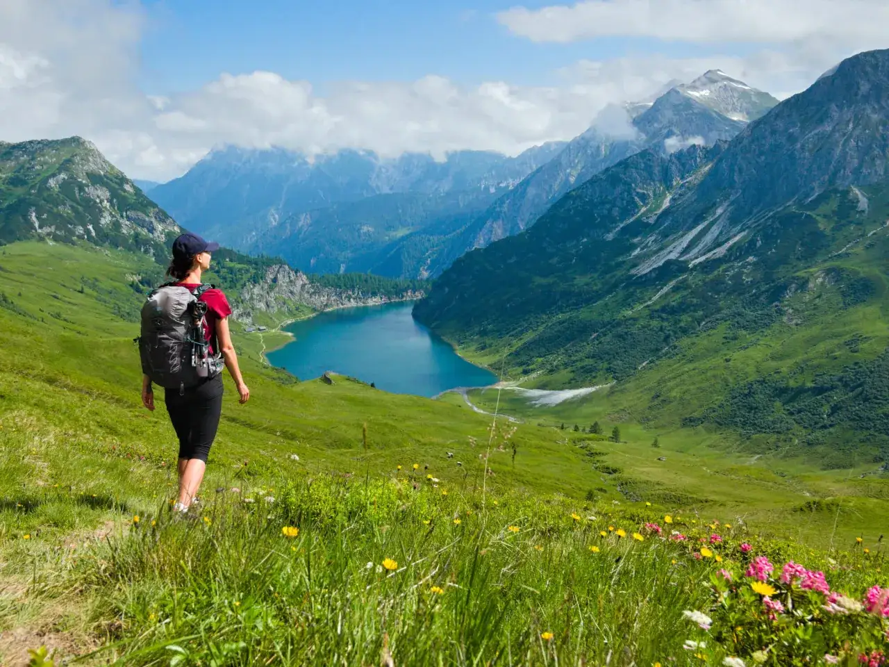 Wanderin mit Rucksack genie&szlig;t den atemberaubenden Ausblick auf einen Bergsee. Perfekter sommerurlaub in Bayern.