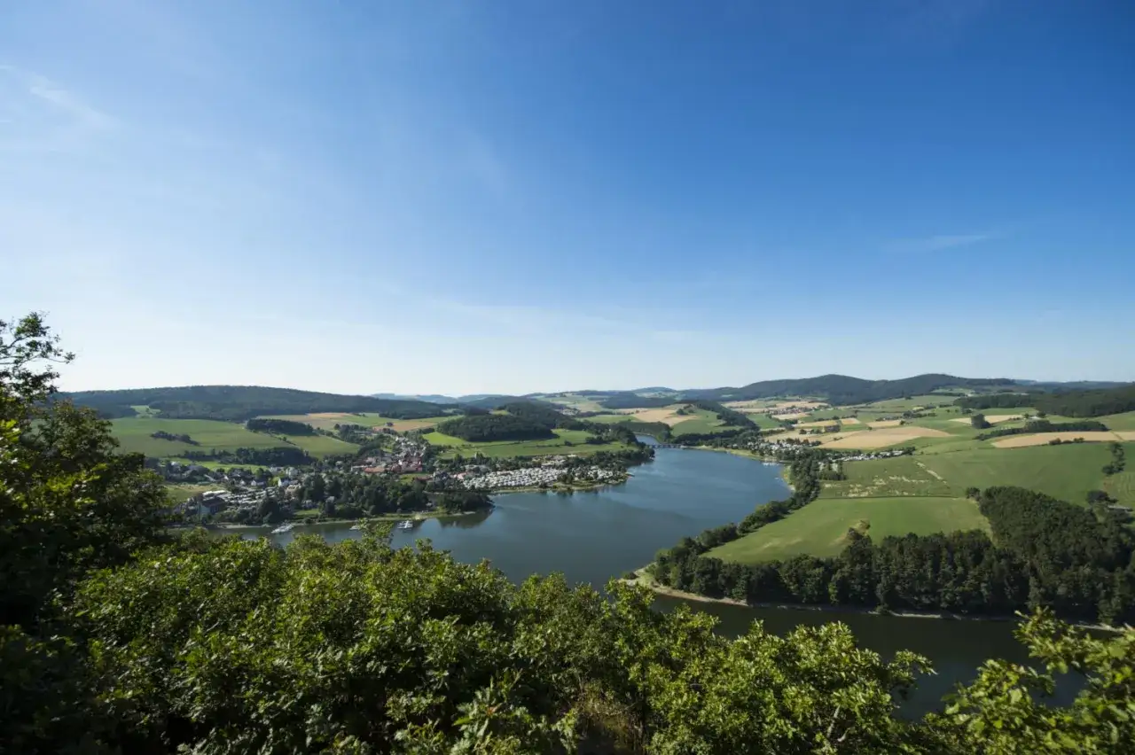 Idyllischer Blick auf einen See mit Campingplatz und Dorf. Perfekt für einen Urlaub in Hessen.