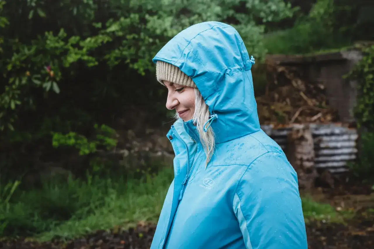 Frau im Regen mit blauer Gore-Tex-Jacke. Richtiges Gore-Tex waschen erhält die Imprägnierung.