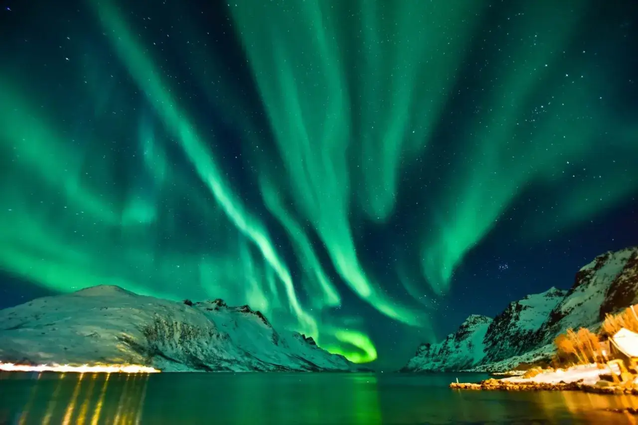 Gr&uuml;ne Nordlichter tanzen &uuml;ber schneebedeckte Berge und einen ruhigen Fjord. Ein magischer norwegischer Wintertraum.
