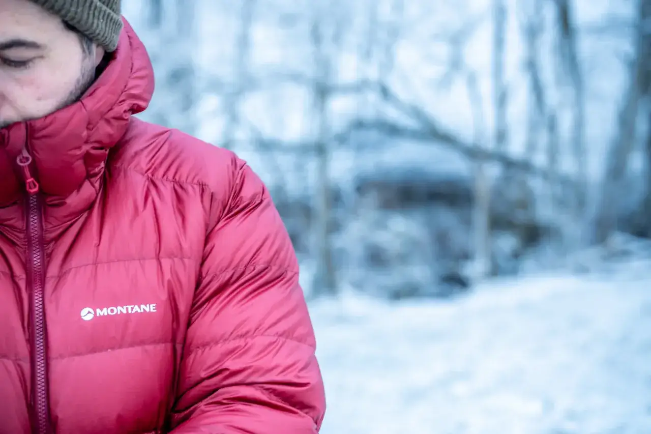 Mann in roter Daunenjacke, die ihn vor K&auml;lte sch&uuml;tzt. Was sind Daunen? Sie sind die feinen, isolierenden Federn von G&auml;nsen und Enten.