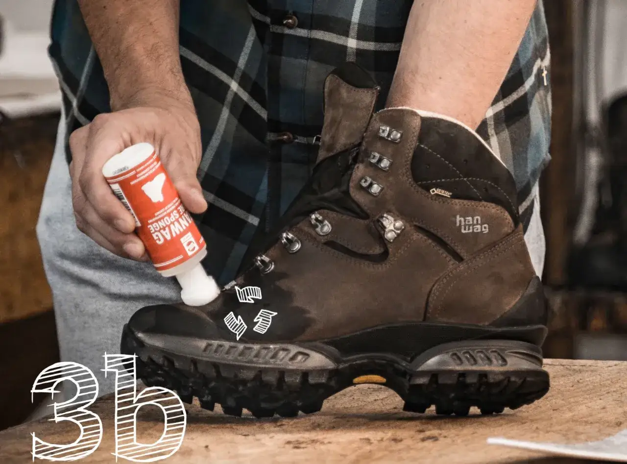 Hanwag Schuhe pflegen: Eine Hand tr&auml;gt mit einem Schwamm eine Pflegefl&uuml;ssigkeit auf einen braunen Lederstiefel auf.