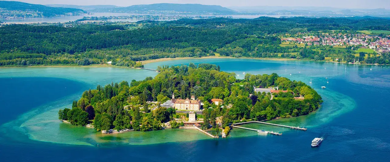 Grüne Insel mit Schloss am Bodensee. Hier kann man viel unternehmen: Bootsfahrten, Spaziergänge und die Natur genießen.