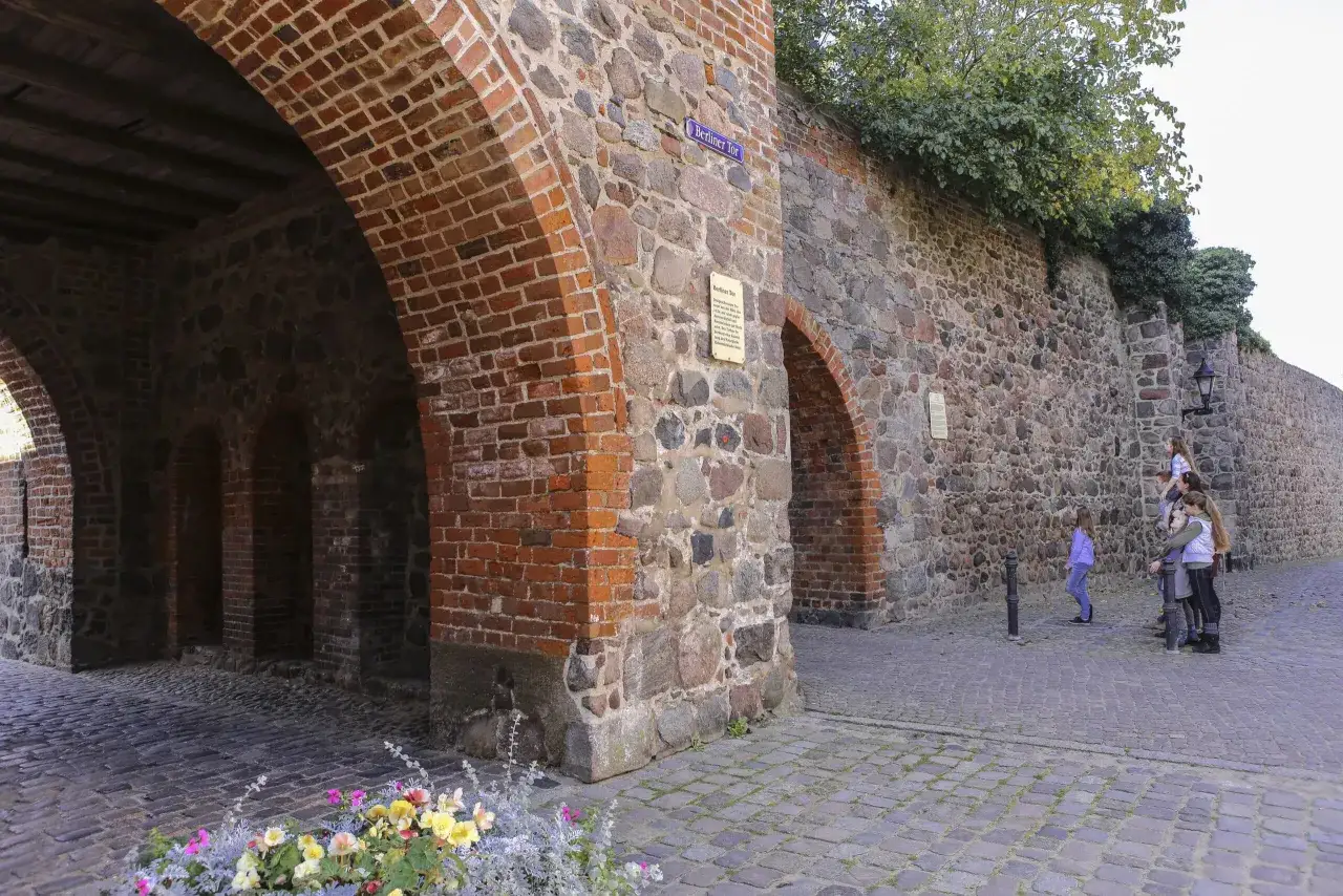 Tor in der Templin Altstadt mit Steinmauer und Ziegelb&ouml;gen. Kinder bestaunen die historische Fassade.