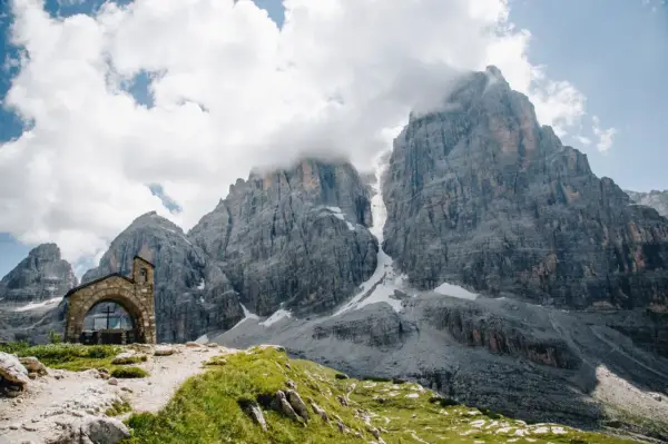 Kleine Kapelle vor imposanten Felsriesen in den Alpen. Ein perfekter Ort für mehrtageswanderungen in Europa.