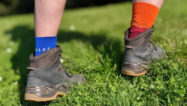 Falke TK1, TK2, TK3, TK4 Socken in Blau und Orange, getragen mit Wanderschuhen im Gras.