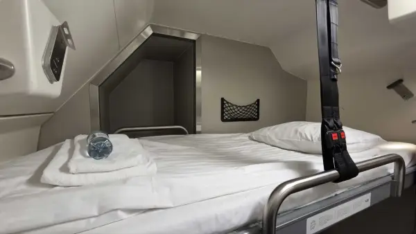 Gemütliches Bett im Schlafwagen, bereit für die Reise mit dem Santa Claus Express. Mit Handtüchern und Wasserflasche.