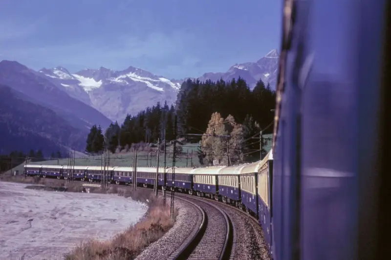 Der Istanbul Express fährt durch eine malerische Berglandschaft mit schneebedeckten Gipfeln und dichten Wäldern.