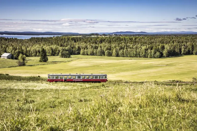 Roter Zug fährt durch grüne schwedische Landschaft. #Inlandsbanan.