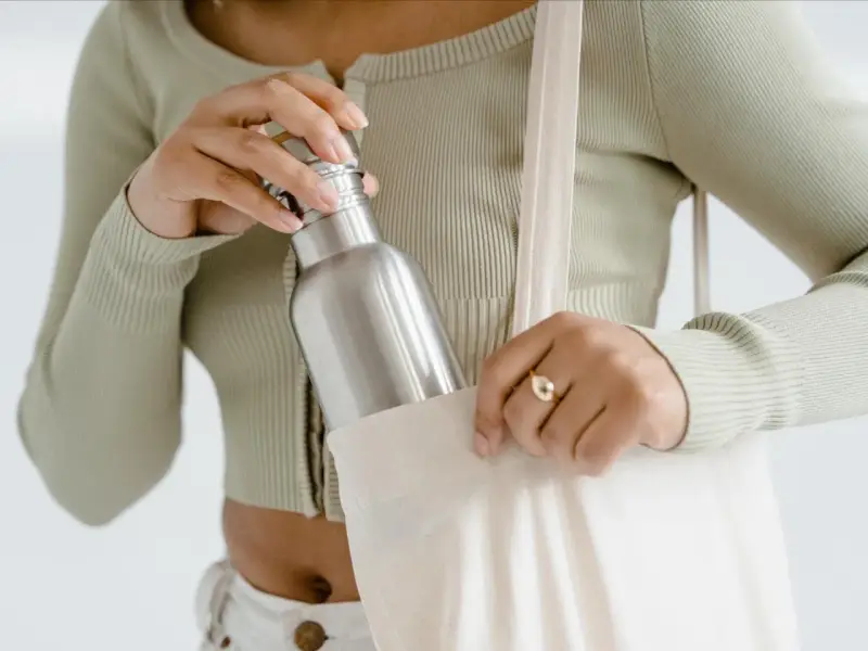 Frau verstaut ihre Edelstahlflasche in einer Stofftasche. So bleibt sie unterwegs sauber und bereit für die nächste Füllung.