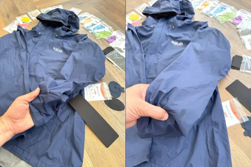 Blaue Regenjacke reparieren: Ein Loch im Ärmel wird mit einem Reparaturflicken ausgebessert. Zubehör für die Regenjacke liegt bereit.
